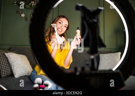 Influencer nimmt zu Hause eine Schönheitsroutine auf. Sie benutzt Ringlicht und Smartphone. Stockfoto