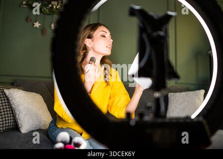 Influencer nimmt zu Hause eine Schönheitsroutine auf. Sie benutzt Ringlicht und Smartphone. Stockfoto