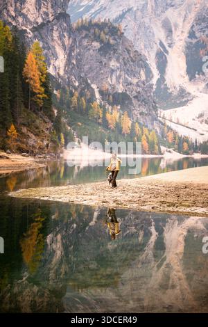 Frau, die im Herbst mit Hund entlang des Pragser Lago in den Dolomiten wandert Stockfoto