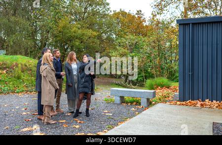 Immobilienmakler zeigt dem Investorenteam modernes umweltfreundliches passives Containerhaus auf Wald Stockfoto
