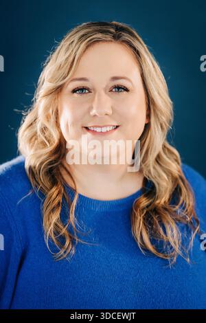 Frau lächelt mit blonden Haaren auf blauem Hintergrund Stockfoto