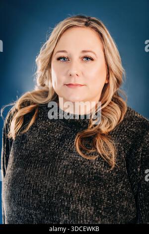 Blonde Frau mit Pullover und Blick in die Kamera Stockfoto