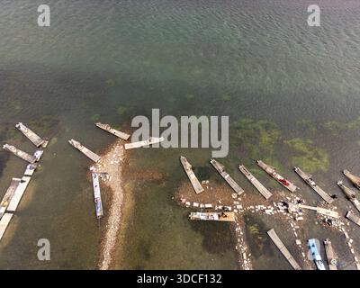 Aus der Vogelperspektive auf Boote, die entlang einer zerklüfteten Küste vertäut sind, wo das smaragdgrüne Wasser auf die Küste trifft, Yangshuo, Guangxi, China. Stockfoto