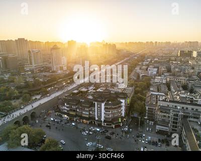 Blick aus der Vogelperspektive auf das Sonnenlicht, das die Skyline der Stadt umspült, lange Schatten über die Gebäude wirft und ein warmes, goldenes Ambiente schafft, Xi'an, Shaanxi, Chin Stockfoto