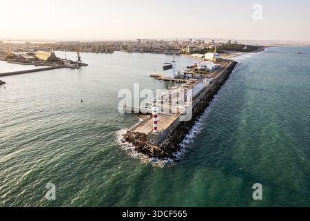 Aus der Vogelperspektive eines markanten rot-weißen Leuchtturms, der am Hafeneingang Wache steht, wo das Meer auf die Stadt trifft, Hafen von Burgas, Burgas, Bulgar Stockfoto