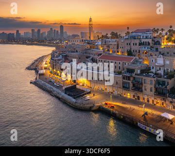 Aus der Vogelperspektive auf die alte Hafenstadt Jaffa, die die moderne Skyline von Tel Aviv bei einem feurigen Sonnenuntergang trifft, Tel Aviv-Yafo, Bezirk Tel Aviv, Israel. Stockfoto
