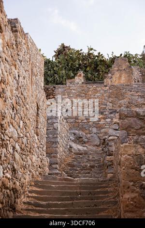 Alte Steintreppe zwischen Festungsmauern auf der Insel Spinalonga, Kreta Griechenland. Historische venezianische Festungsruinen mit Verteidigungsarchitektur. Stockfoto