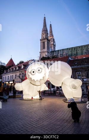 Zagreb, Kroatien - 16. März 2023: Blick auf beleuchtete Skulpturen, die vor der Kulisse der Türme der Zagreber Kathedrale und eines dunklen Himmels stehen. Stockfoto