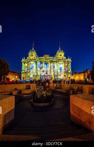 Zagreb, Kroatien - 16. März 2023: Blick auf das Kroatische Nationaltheater, das in einer lebendigen Lichtshow getaucht ist, die vom nassen Stein reflektiert und den Ei zieht Stockfoto