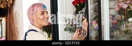 Eine junge Floristin mit gefärbten Haaren arrangiert in ihrem lebhaften Geschäft, Banner, gerne Blumen Stockfoto