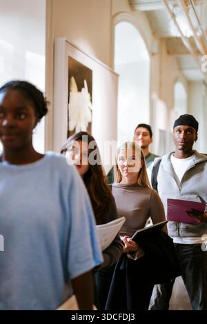 Junge Frau wartet in Schlange mit Freunden auf dem Universitätscampus Stockfoto