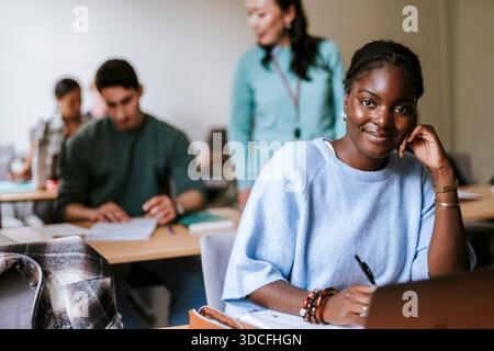 Porträt einer lächelnden jungen Frau, die im Klassenzimmer am College sitzt Stockfoto