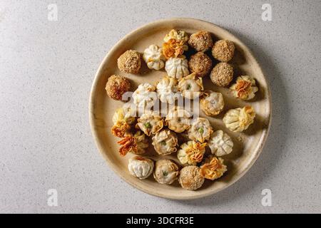 Dim Sum Gyozas asiatische gebratene Knödel Partei in Keramik Platte über Grau gefleckten Hintergrund gesetzt. Flach, Raum Stockfoto
