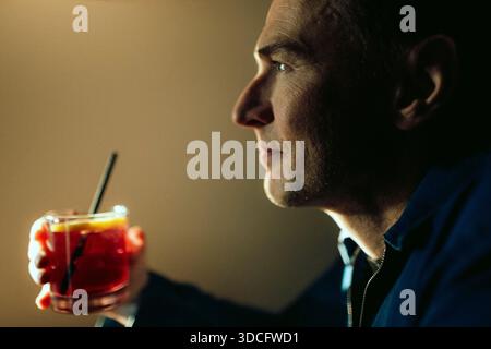 Nahaufnahme eines nachdenklichen Mannes, der ein Glas Getränk hält Stockfoto