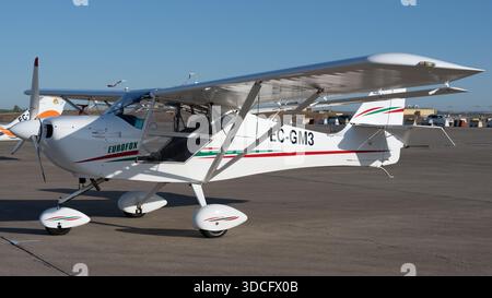 Moron, Spanien - 12. Mai 23: Ein Weißlichtflugzeug mit roten und grünen Streifen parkt auf einem Flughafenparkplatz Stockfoto