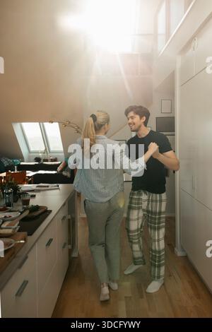 Ein lächelndes junges Paar, das zu Hause in der Küche tanzt. Am sonnigen Morgen Stockfoto