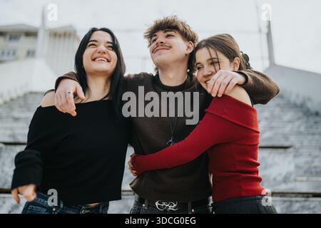 Drei Freunde umarmen und lächeln gemeinsam im Freien und halten einen fröhlichen Teenager-Moment fest Stockfoto