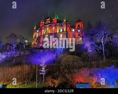 Festliche Szenen vom Edinburgh Christmas Market mit leuchtenden Ständen, beleuchteten Gebäuden und einem riesigen beleuchteten Edinburgh Schild schaffen eine lebendige Szene. Stockfoto
