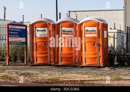 Eine Reihe von drei orangen Boels Leihtoiletten, die an einem sonnigen Tag auf einem gepflasterten Bürgersteig in der Nähe einer Baustelle stehen. Nieuwegein Niederlande, 21 Nov Stockfoto