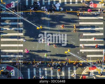 Aus der Vogelperspektive sehen Fußgänger, die die Straße an einem Quersteg überqueren und lange Schatten in die urbane Landschaft von Brooklyn, New York, USA, werfen. Stockfoto