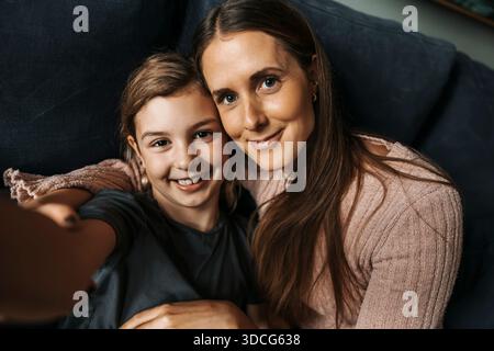 Porträt eines lächelnden Mädchens, das zu Hause Selfie mit Mutter macht Stockfoto