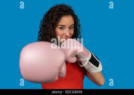 Athletin lächelt und posiert mit rosa Boxhandschuhen, zeigt Stärke und Ermächtigung Stockfoto