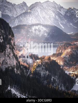 Blick auf das Schloss Neuschwanstein, eingebettet zwischen schneebedeckten Kiefern, eine märchenhafte Festung vor dem Hintergrund hoch aufragender, schneebedeckter Berge und einer ruhigen Atmosphäre Stockfoto
