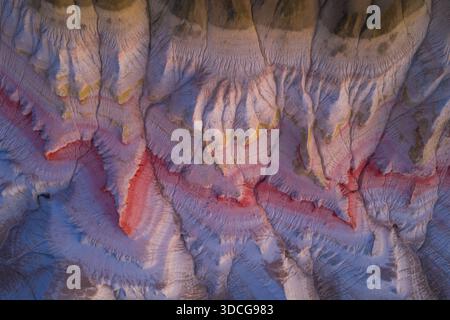 Aus der Vogelperspektive auf eine surreale Landschaft zeigt die Kunstfertigkeit der Natur mit leuchtenden Rot- und Weißtönen, strukturiertem Gelände und Schatten, Bokty, Mangystau Region, Stockfoto