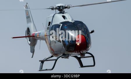 Moron, Spanien - 12. Mai 23: Ein Patrulla ASPA Hubschrauber fliegt in den Himmel, während eine Person aus dem Fenster winkt Stockfoto