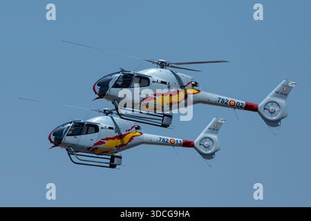 Moron, Spanien - 12. Mai 23: Zwei Patrulla ASPA Hubschrauber fliegen in Formation gegen einen klaren blauen Himmel Stockfoto
