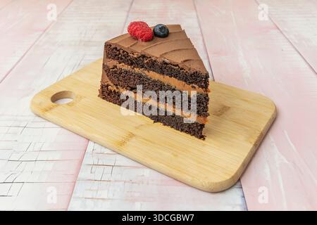 Schokoladenkuchen mit geschmolzenem Schokoladenzentrum, das beim Schneiden austretet, warm serviert mit einem Messlöffel Vanilleeis und Himbeersauce. Stockfoto