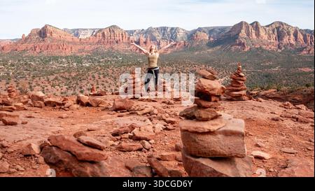 Blick auf eine Frau, die zwischen ausgeglichenen felsenhügeln auf einem roten Felsplateau steht, Silhouetten vor weit entfernten Mesas, Desert Hills, Arizona, USA. Stockfoto