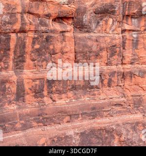 Blick auf die geschichteten roten Felsformationen, die die rauen Strukturen und dunklen Streifen zeigen und die geologische Geschichte der Wüste, Desert Hills, Ariz, zeigen Stockfoto