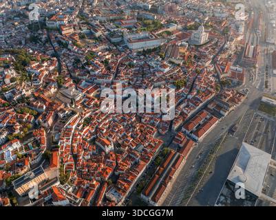 Blick aus der Vogelperspektive auf die Terrakotta-Dächer, die in Richtung des majestätischen Pantheons kaskadieren, wo Schatten mit der goldenen Umarmung der Sonne tanzen, Lissabon, Portugal Stockfoto