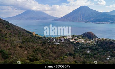 Aus der Vogelperspektive auf den riesigen, glitzernden See Atitlán, umgeben von majestätischen Vulkanen, mit der Stadt eingebettet in üppige Hügel, Lake Atitlan, Departme Sololá Stockfoto