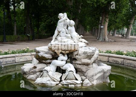 Ein dekorativer Brunnen mit Cherubiskulpturen, umgeben von Grün und einem Pfad Stockfoto