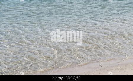 Kristallklares Strandwasser, das sanfte weiße Sandküste am Calm Sea Sunny Day Relaxing Stockfoto