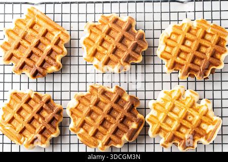 Belgische Waffeln auf einem schwarzen Metallgestell auf einem weißen Tisch. Blick von oben. Hochwertige Fotos Stockfoto