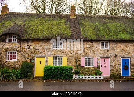 Lulworth Cove, Dorset 12-21-2025 Ein charmantes Steinhaus mit einem Strohdach, mit bunten Türen und Fenstern, Stockfoto