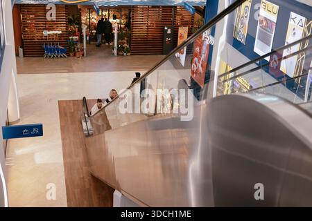 KIEW, Ukraine 2. Dezember 2025 Hochwinkelaufnahme von Menschen auf einer Rolltreppe in einem modernen Einkaufszentrum. Authentischer urbaner Lebensstil mit Schwerpunkt auf Bewegung und Stockfoto