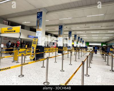 Manchester, Großbritannien - 13. Dezember 2025: Passagiere stehen an der Abfertigung am Flughafen Manchester an, geführt durch gelbe Barrieren und klare Beschilderung. Stockfoto