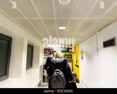 Manchester, Vereinigtes Königreich - 13. Dezember 2025: Menschen laufen durch einen hellen Flur mit Rucksäcken zu Diensten in Manchester. Stockfoto