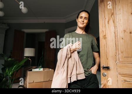Flaches Porträt einer selbstbewussten Frau, die zu Hause mit der Hand in der Tasche steht Stockfoto