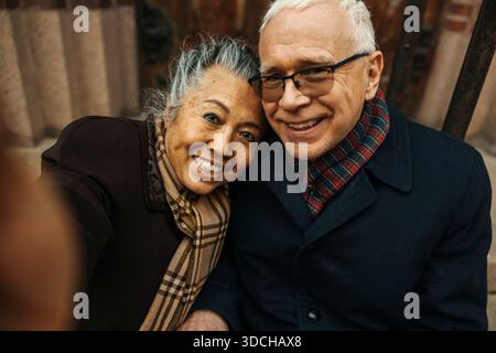 Porträt einer lächelnden Seniorin, die Selfie mit einem Mann macht Stockfoto