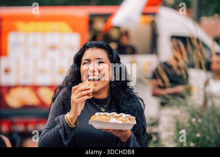 Porträt einer glücklichen jungen Frau, die Hot Dog isst Stockfoto