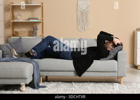 Depressiver junger Mann, der zu Hause auf dem Sofa liegt Stockfoto