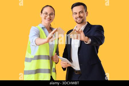 Junge Architekten mit Hausfiguren auf gelbem Hintergrund Stockfoto