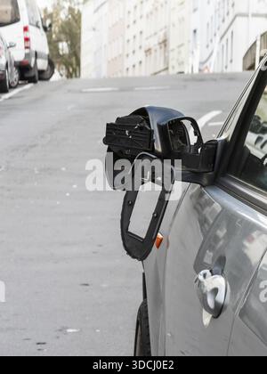 Ein Auto auf der Seite einer steilen Wohnstraße. Der linke Außenspiegel des Fahrzeugs ist stark beschädigt und ein Teil des Spiegels befindet sich auf der Motorhaube, Wuppertal, Stockfoto