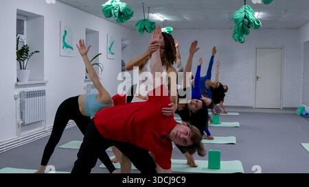 Yogalehrer zeigt einer Gruppe von Schülern eine schwierige Stretchposition. Stockfoto