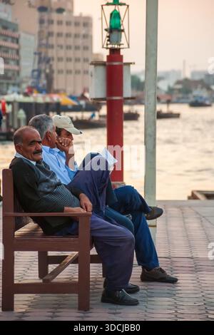 Älterer Mann, der sich auf Einer Holzbank am Ufer mit Einem Boot in der Ferne entspannt Stockfoto